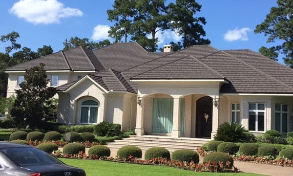 A large house with bushes and trees in front of it.